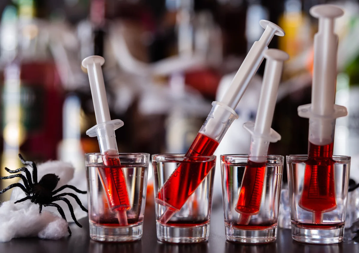 Creepy halloween party shots with syringes of grenadine syrup