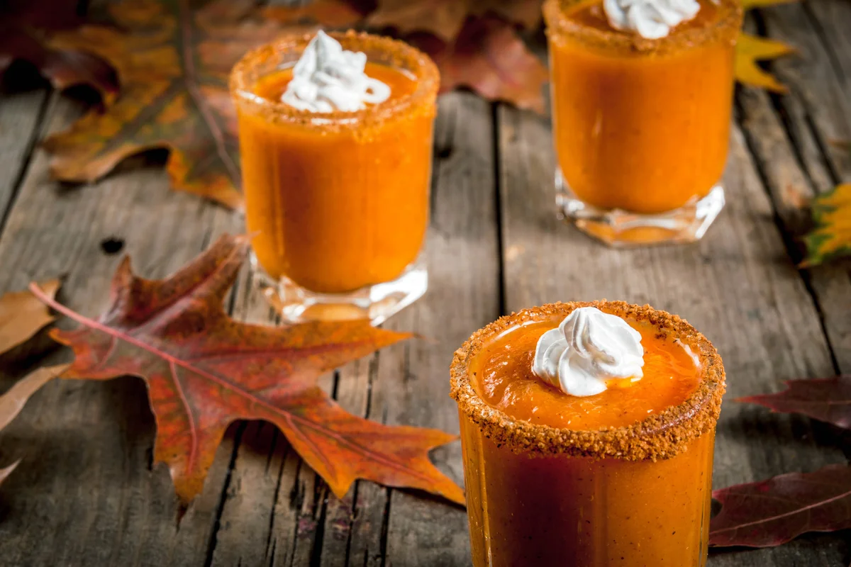 Pumpkin Pie Vodka Shots on old rustic wooden table with fall leaves