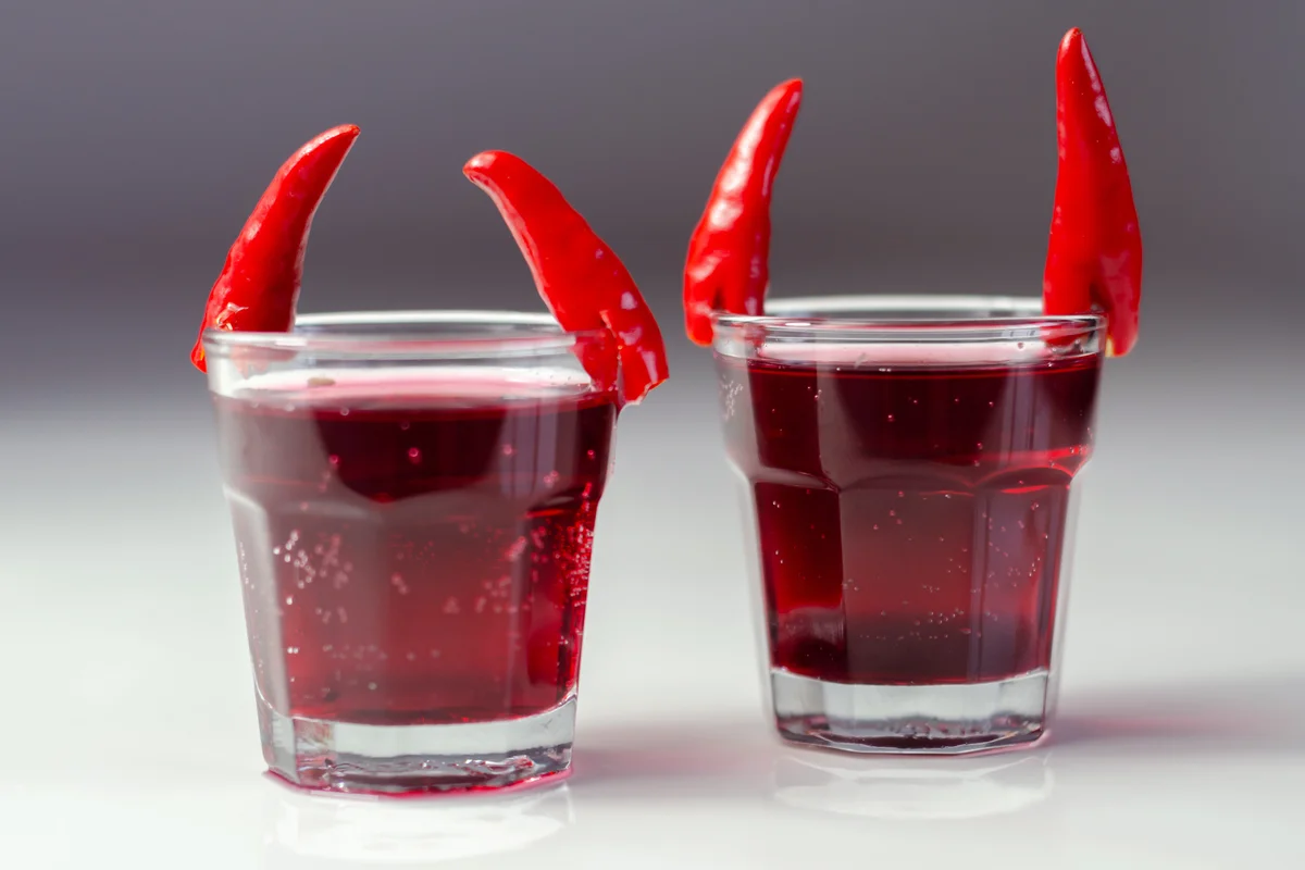 Drink shot prepared with vodka, grenadine and lemon juice decorated with chillies in the shape of horns