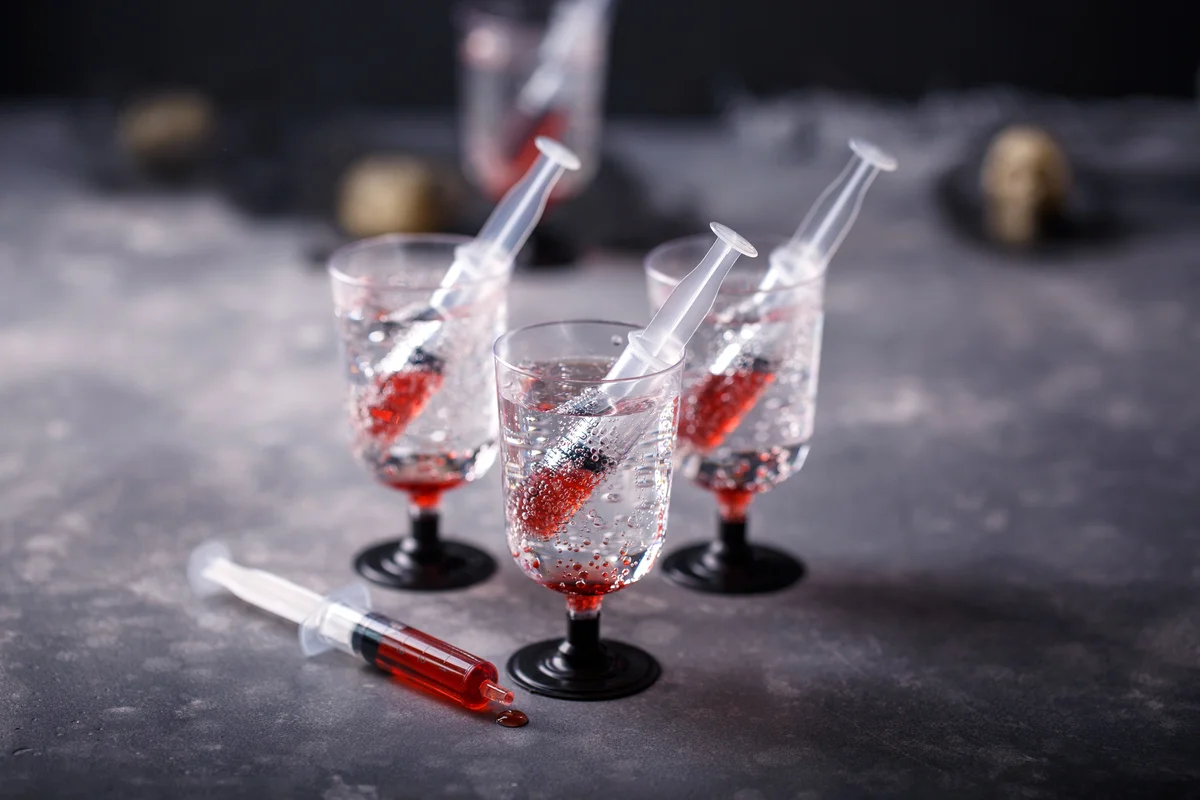 Bloody soda beverage with syringe of red grenadine syrup