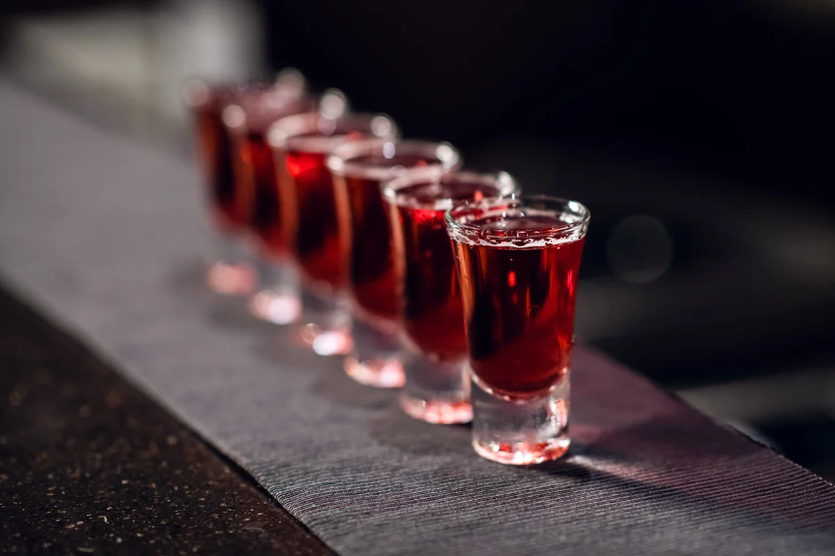 Row of shots with red liquor on the bar