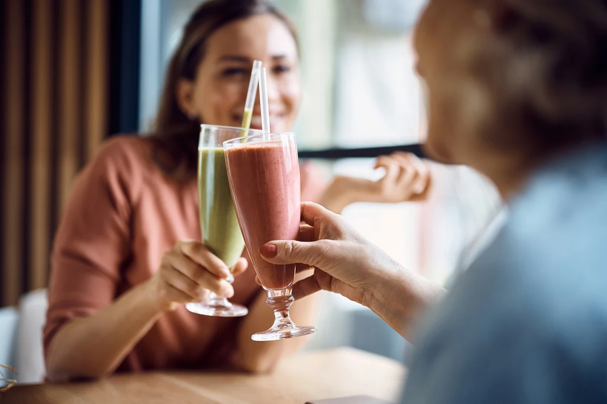 Close-up of mother and daughter toasting while celebrating in a cafe