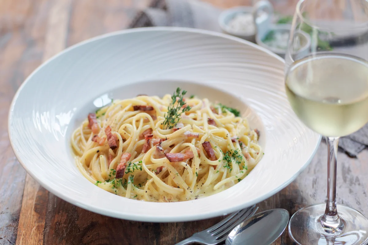 Linguini carbonara made with smoked pancetta and a glass of white wine