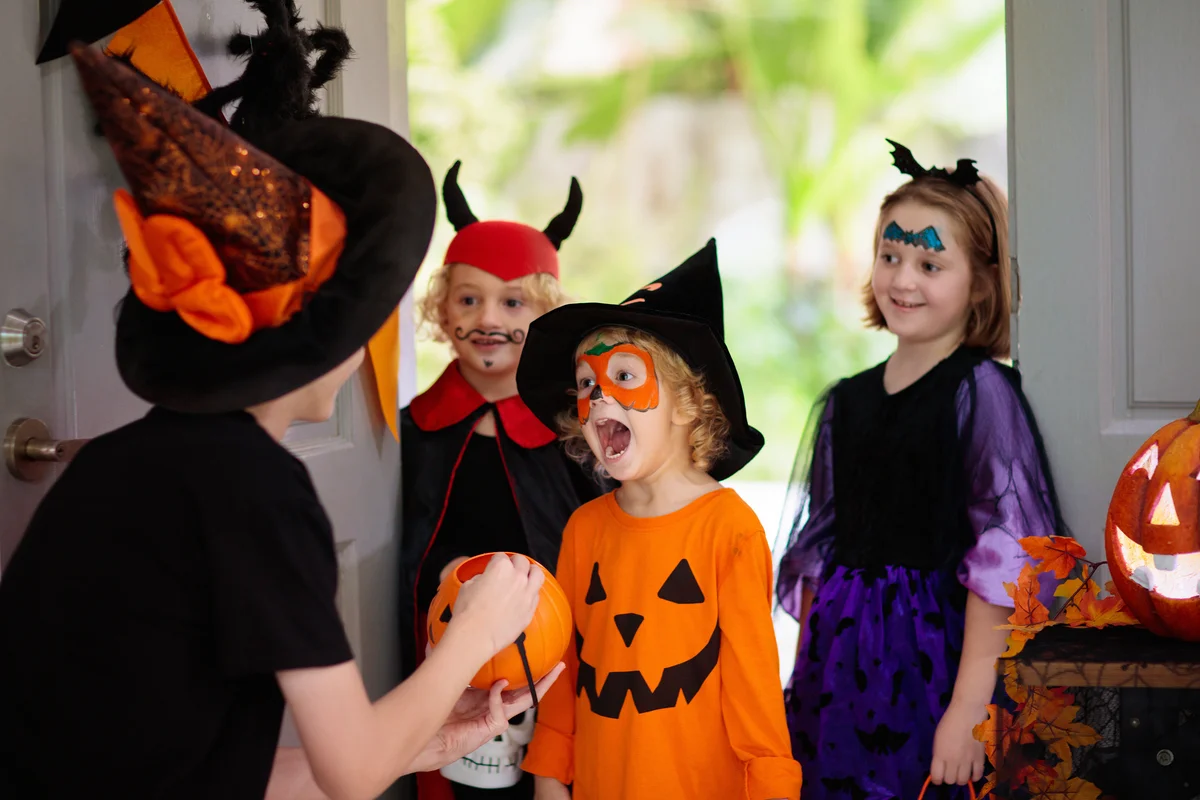 mom in witch costume passing out candy on Halloween