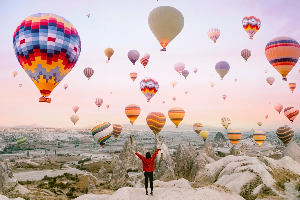 Young woman on a background of flying balloons at sunrise