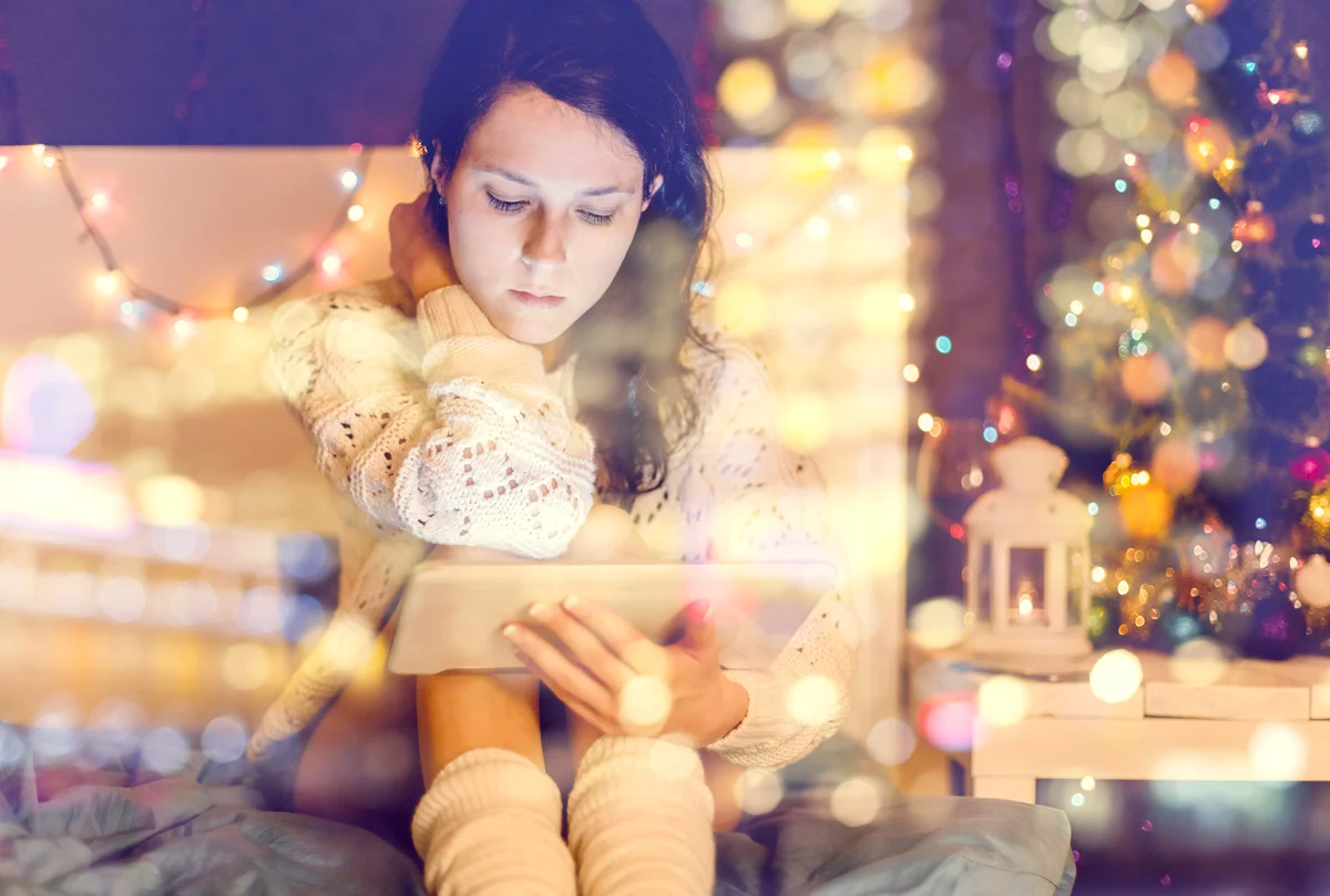 Young woman looking at her tablet felling the holiday blues