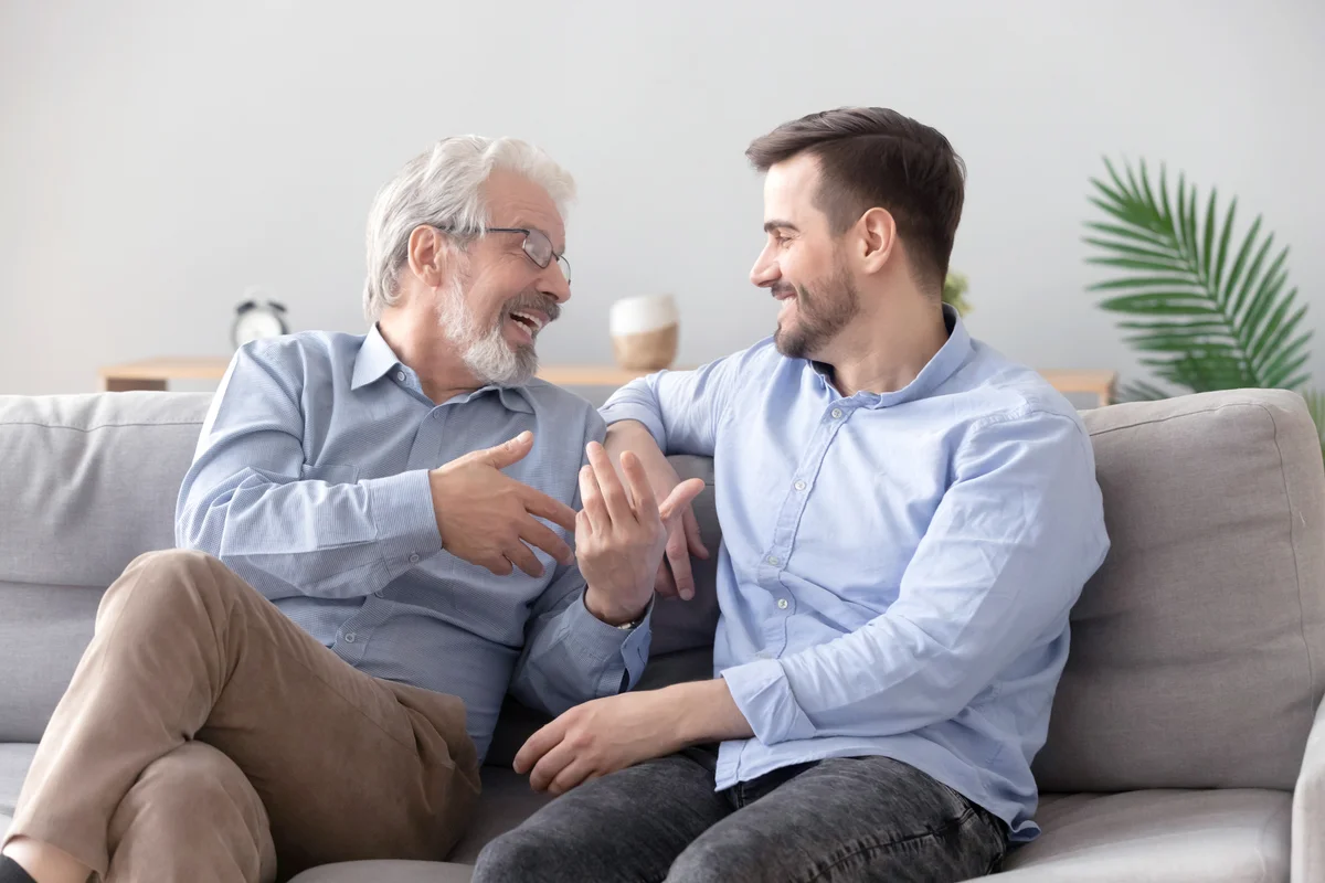Happy father and young son talking on sofa
