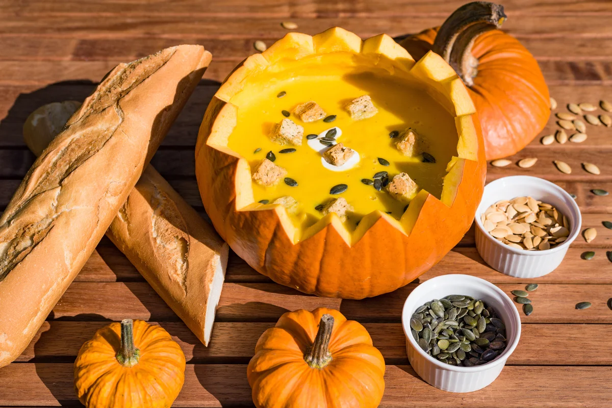 Pumpkin soup in shell served with bread and roasted pumpkin seeds