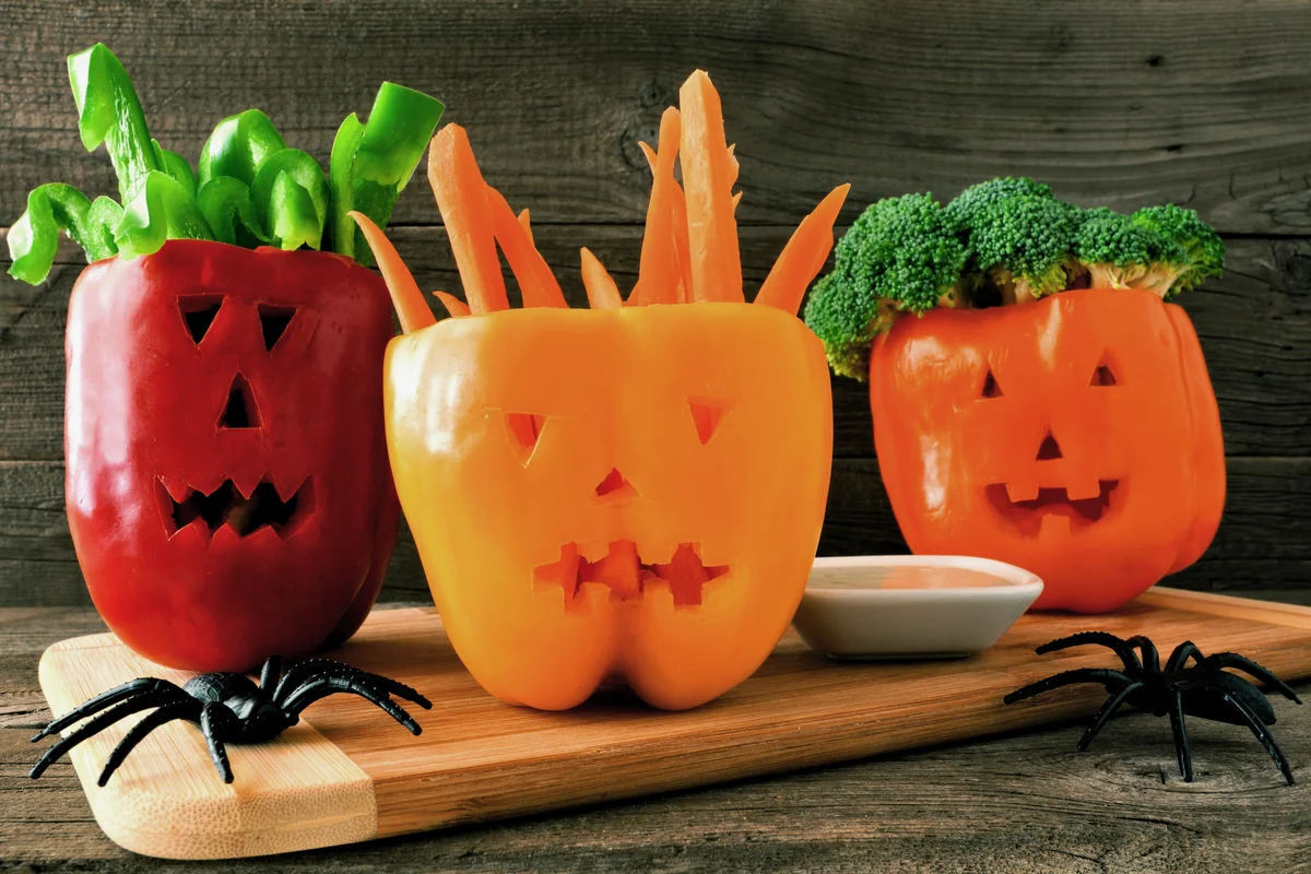 Halloween vegetables and dip in Jack o Lantern peppers on wood