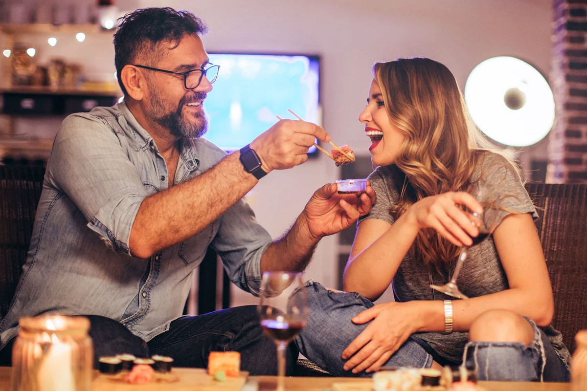 Couple having romantic date night at home eating sushi