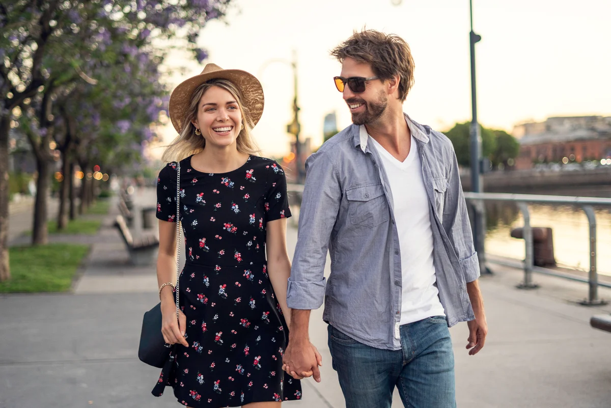 couple walk by river at sunset