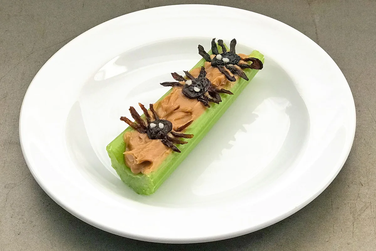 Halloween spiders on a log made from celery, peanut butter, raisins