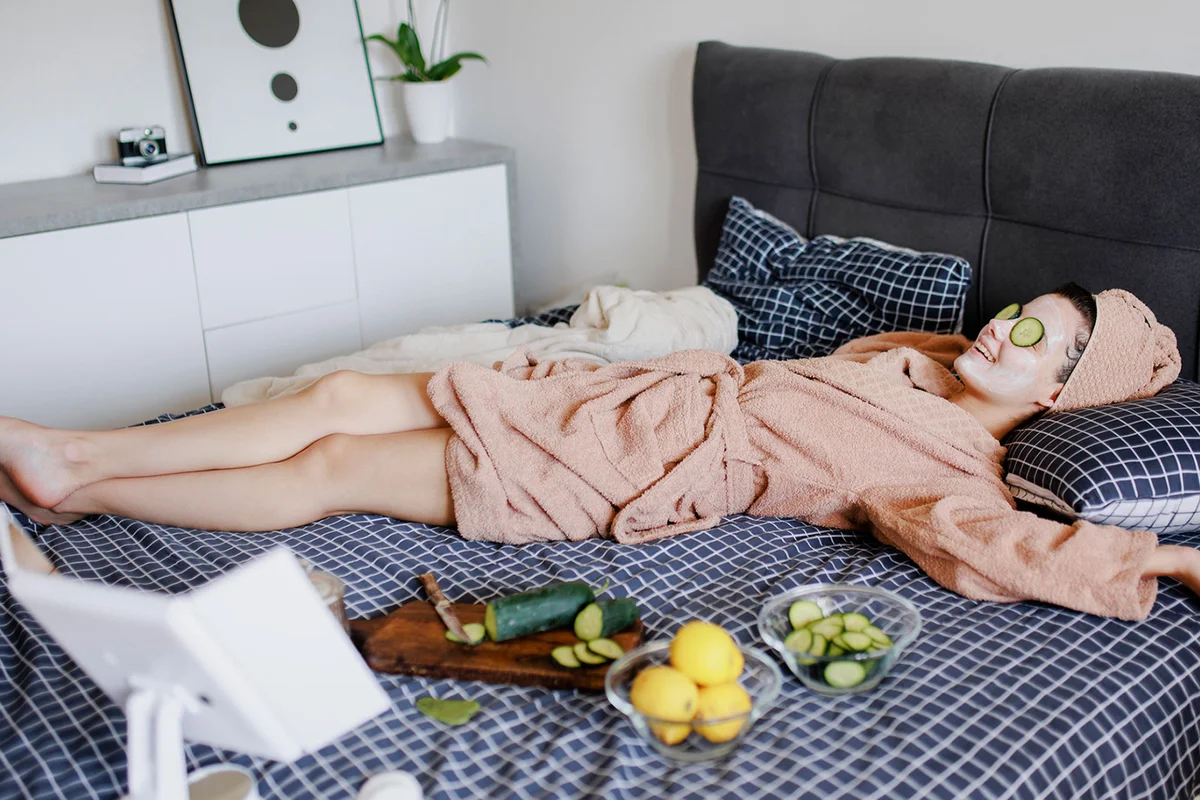woman relaxing on bed with cucumber eye mask