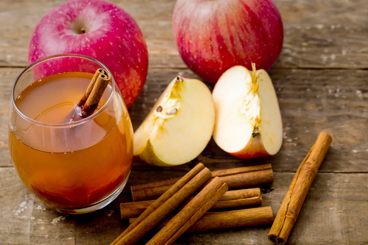 Apple cider with cinnamon stick on wooden background
