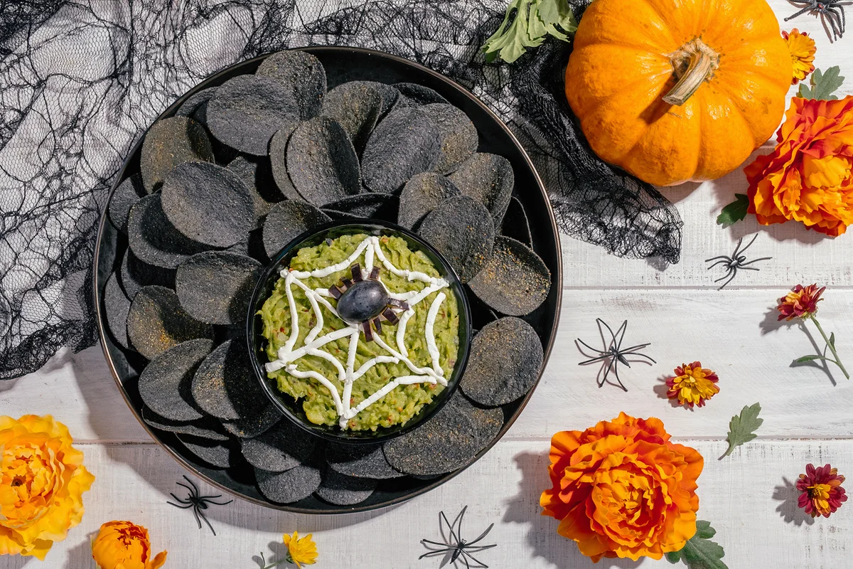 Spooky Halloween black potato chips with guacamole dip