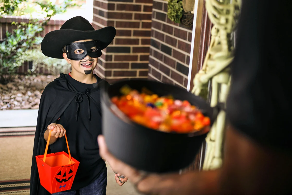 boy in cowboy costume trick or treating at door on Halloween