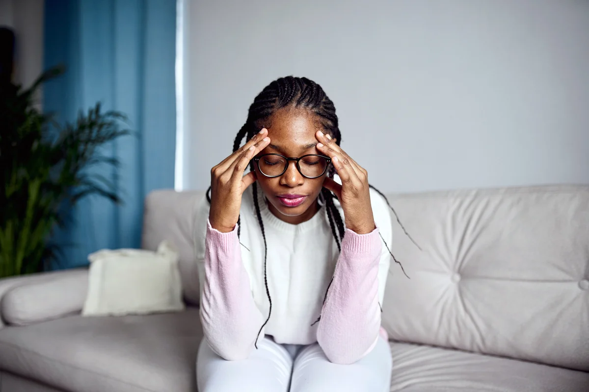 Young girl is sitting on the couch suffering from anxiety