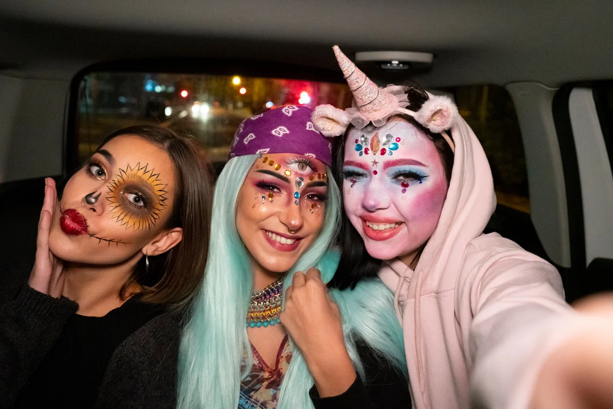 Girls with Halloween costumes taking selfie in the car on the way to a Halloween party
