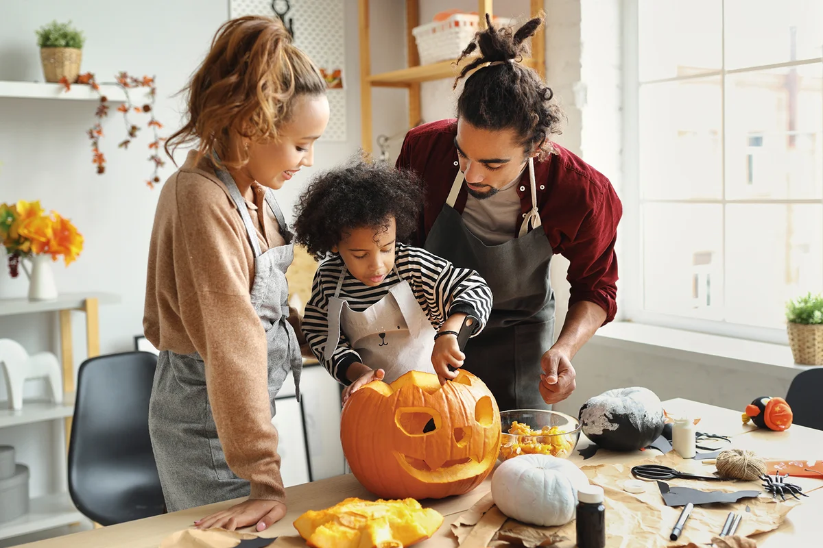 Family carving pumpkin for Halloween holiday together at home