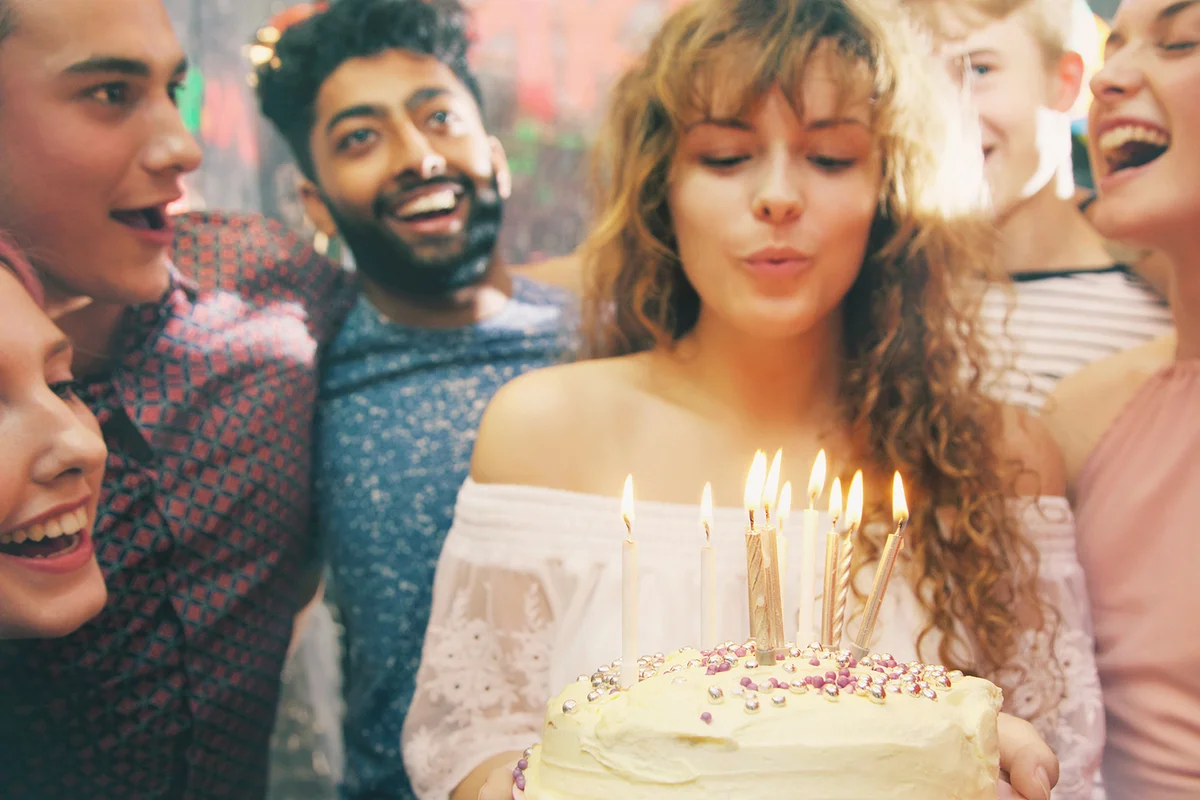 Woman blowing candles while celebrating birthday with friends