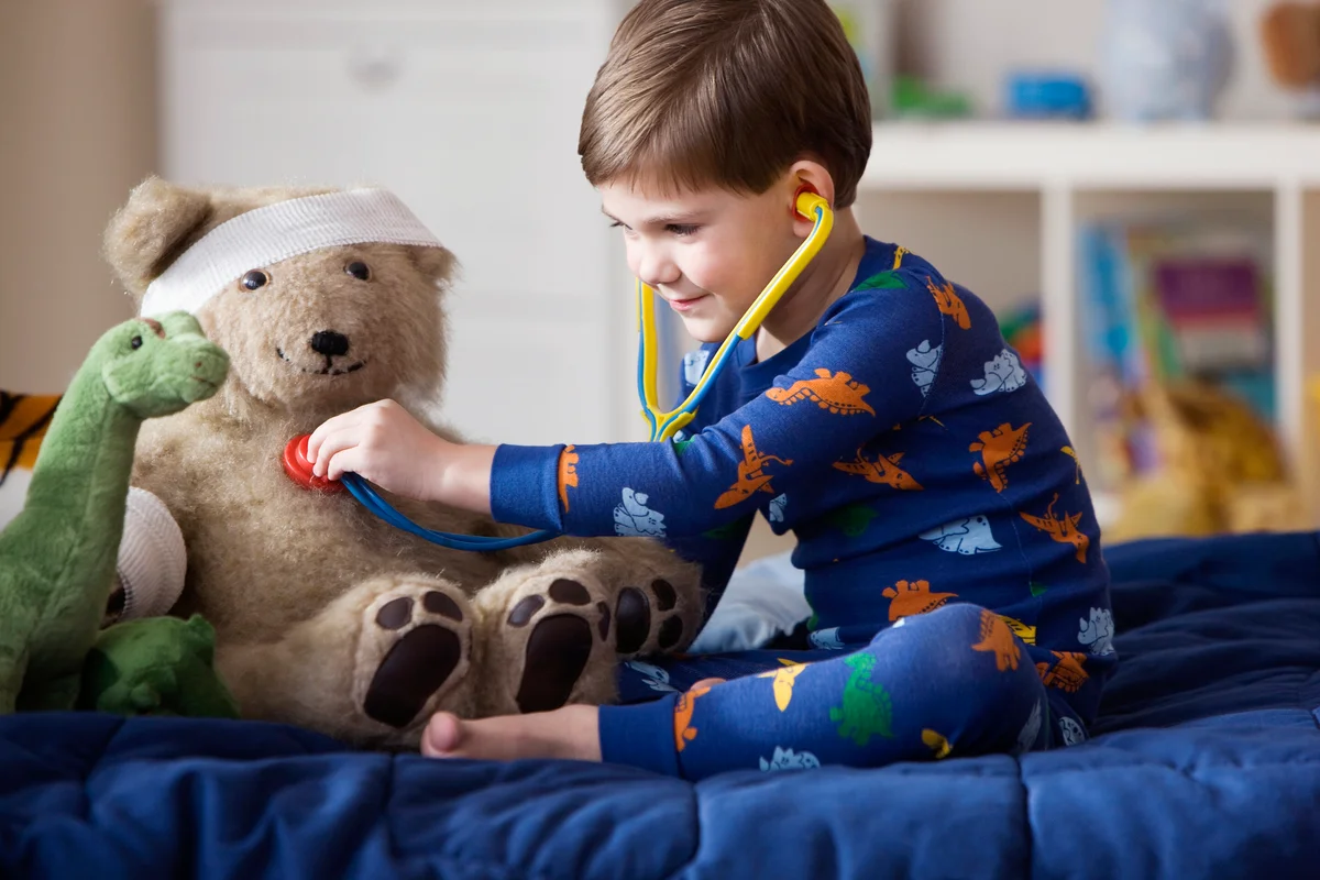 Boy listening to teddy bear's heartbeat with stethoscope