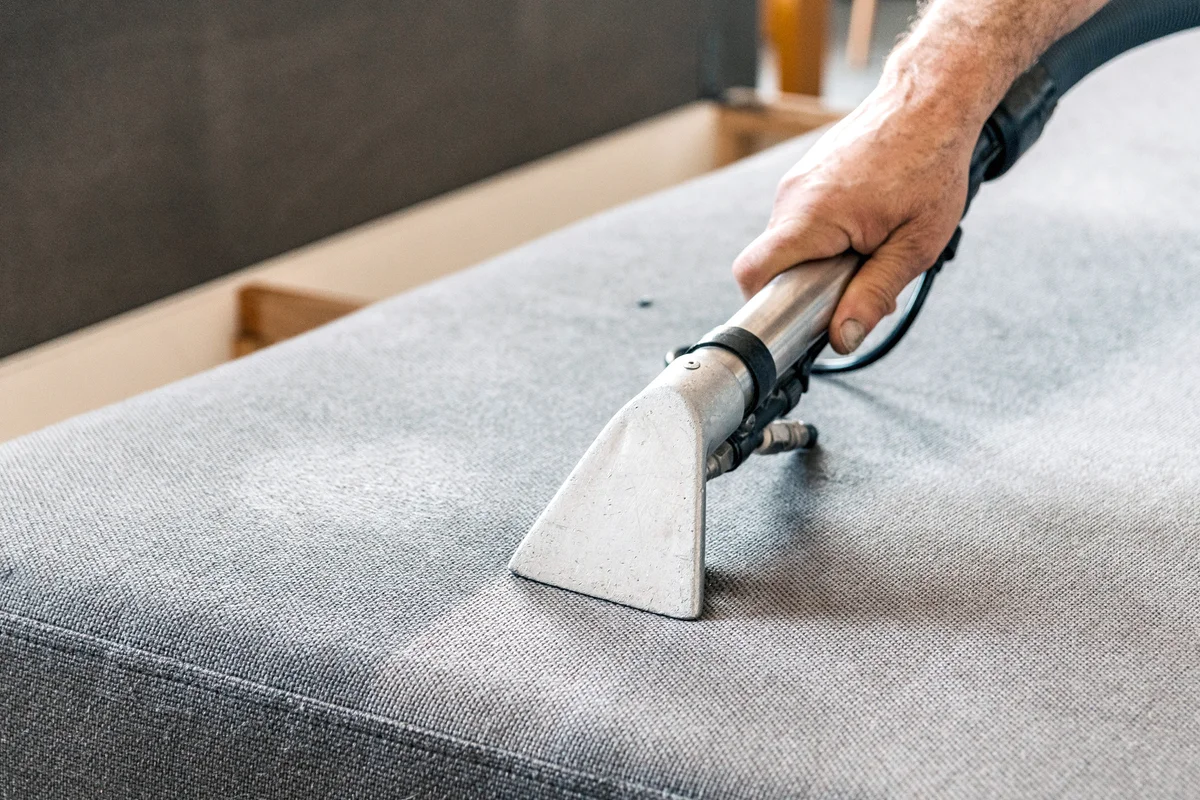 Man Doing A Deep Clean Of Sofa In Living Room