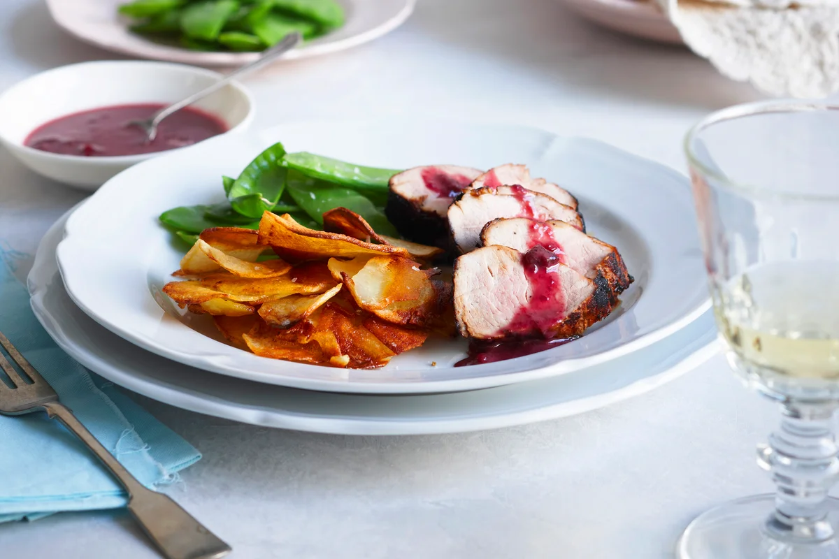 Plate of cherry pork tenderloin and white wine on table