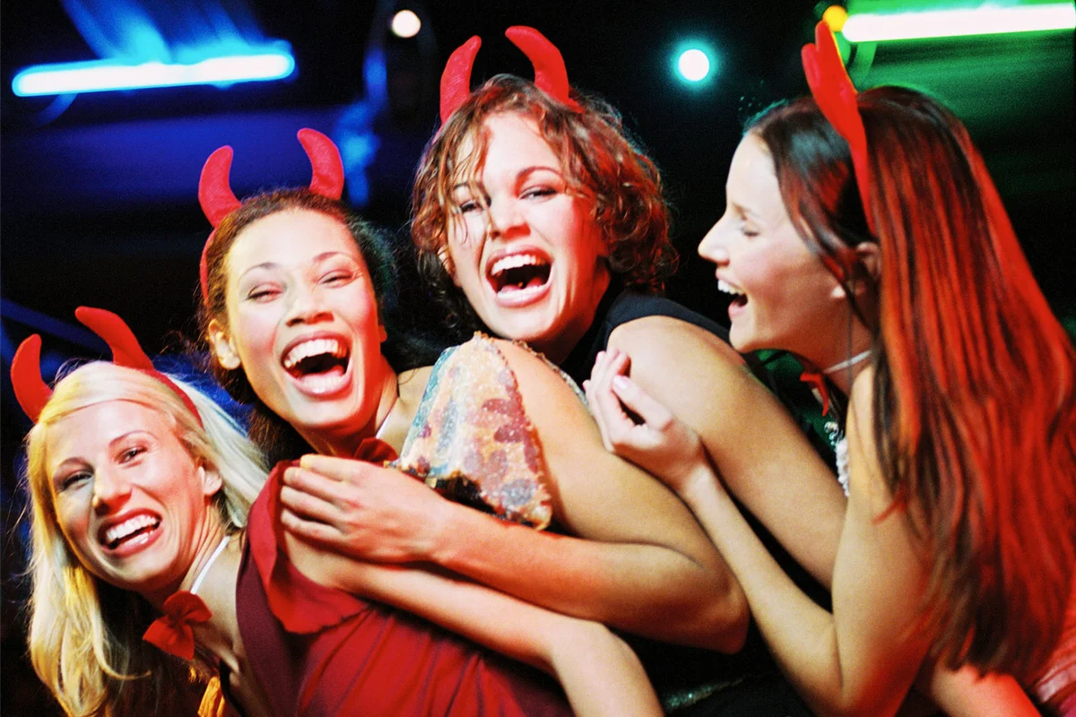 women in devil costumes dancing at party on Halloween