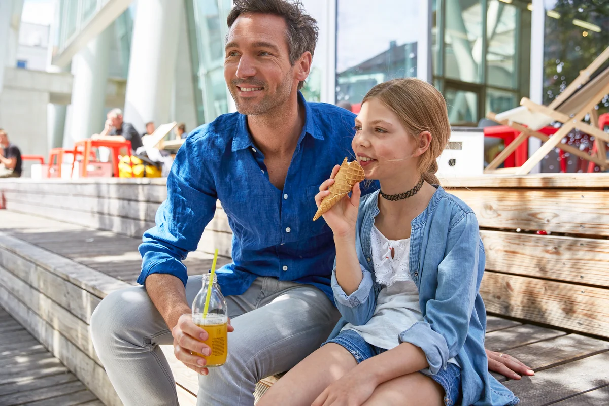 Father with drink and daughter with ice cream cone at an outdoor cafe