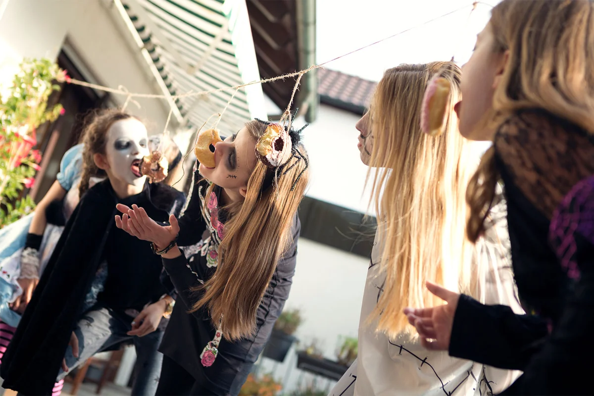 Children at Halloween party having donut eating contest