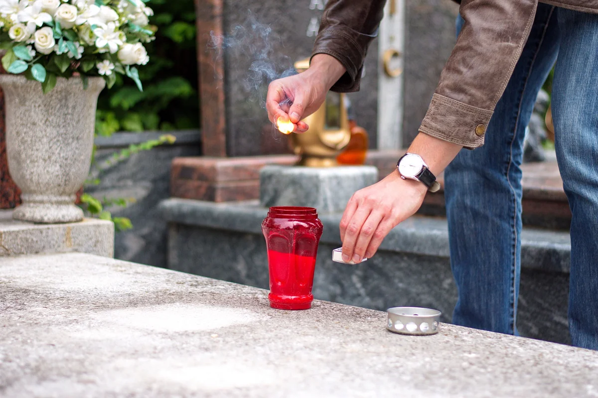 man lighting candle at father's grave