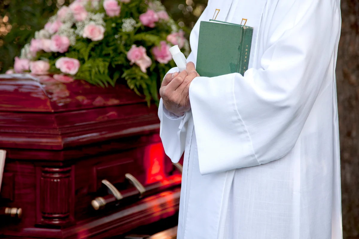 Priest standing near coffin at funeral