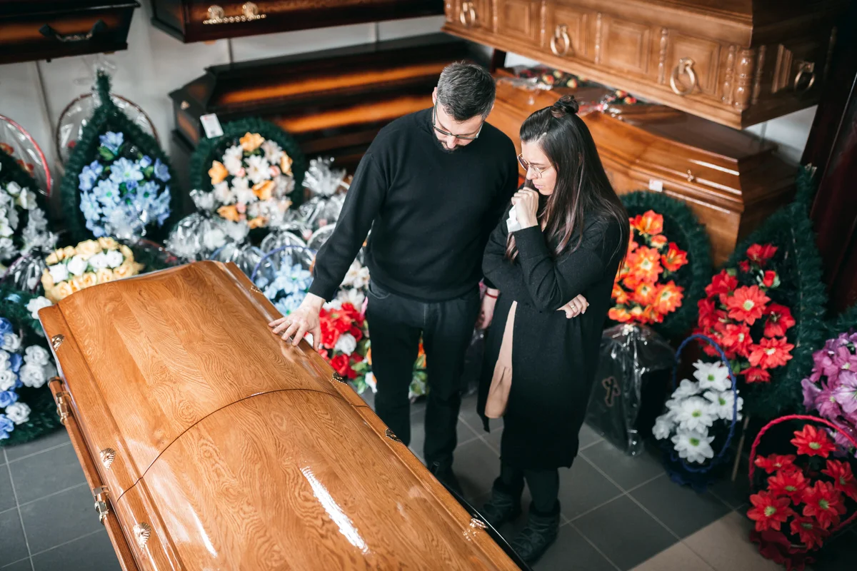 Undertaker showing coffins and crosses to a widow