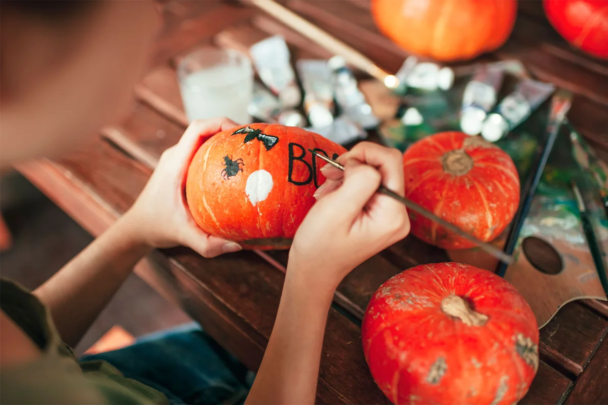 teenager decorating Halloween pumpkin with paint