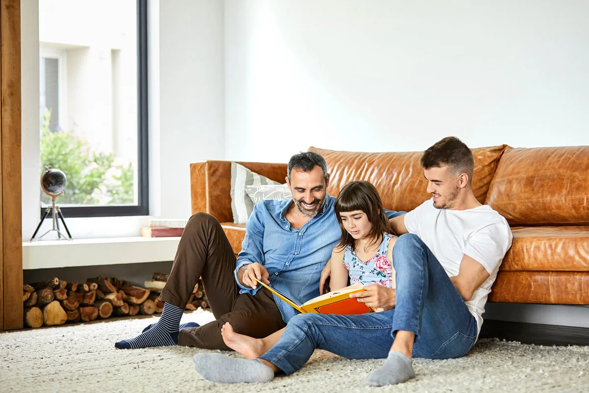 couple with daughter reading book at home