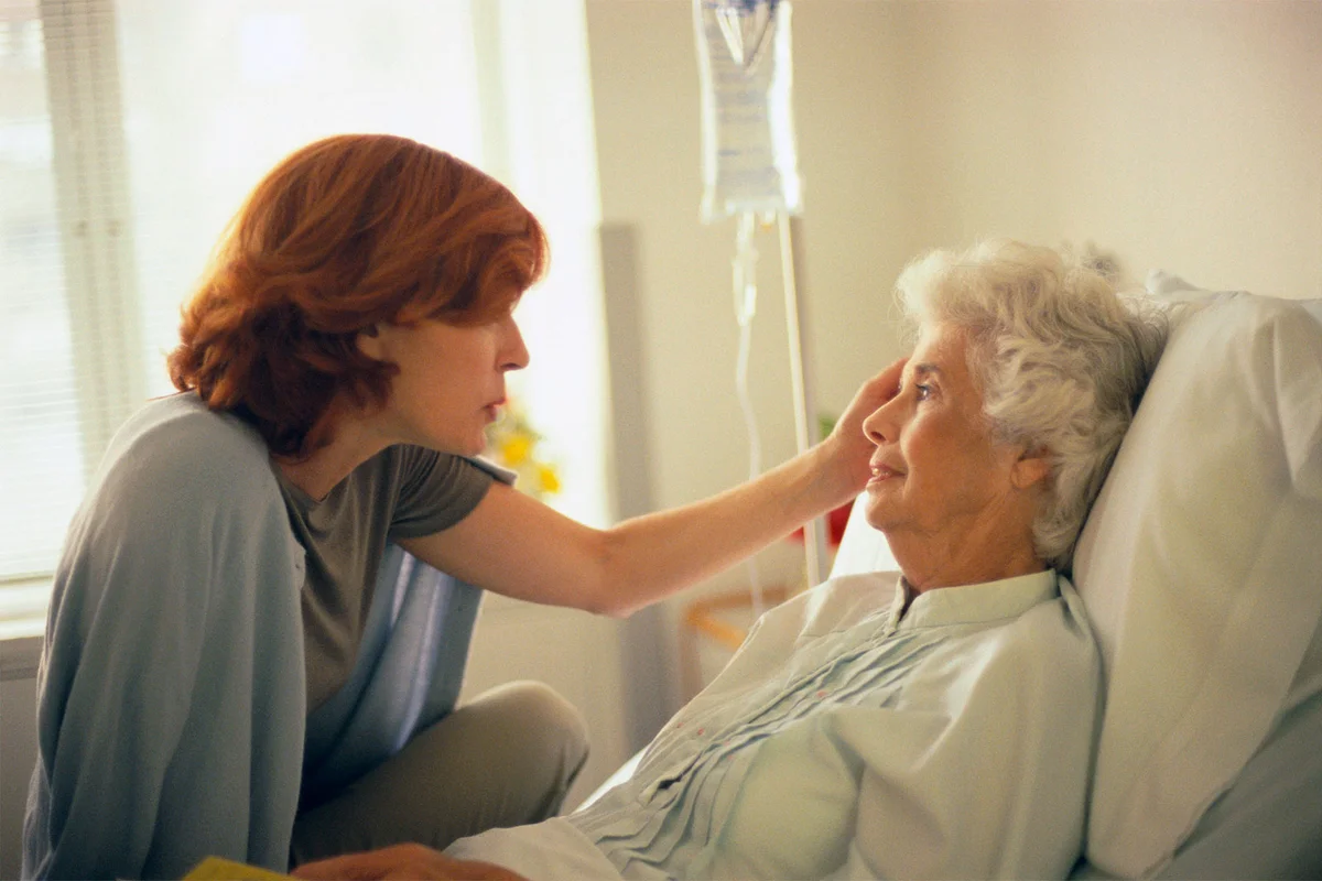 elderly mother in hospital bed talking to grown daughter