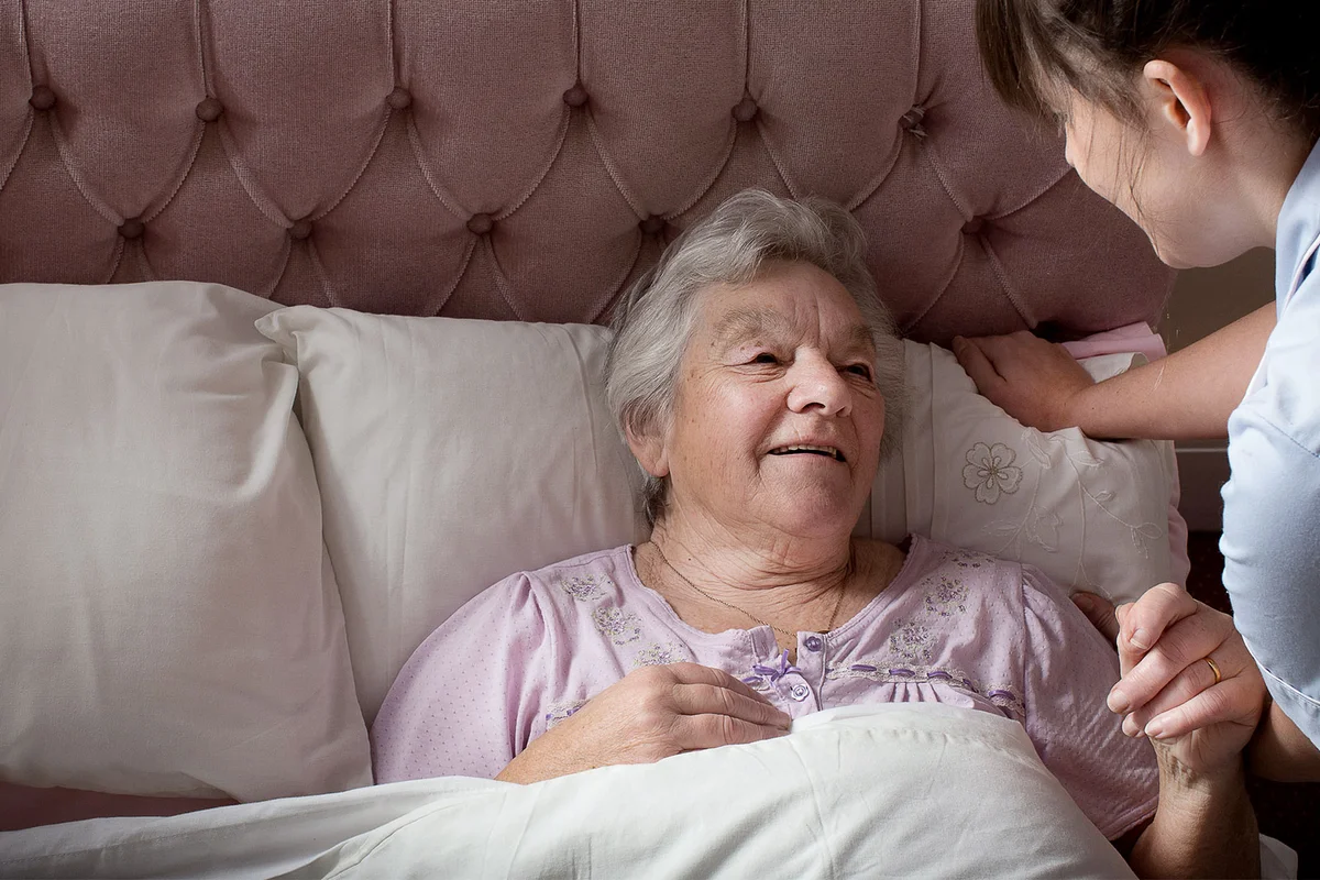 elderly woman in bed at home talking to family member