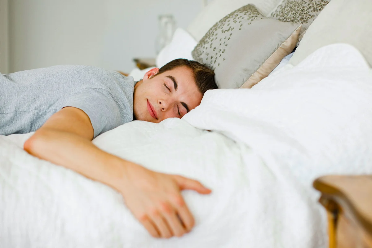 man relaxing in bed while experiencing ASMR