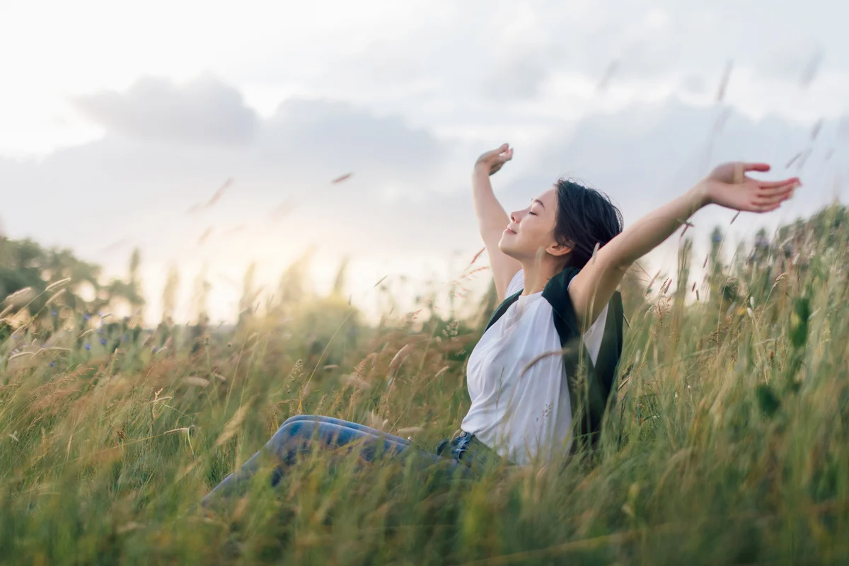 Young Woman Sitting In Meadow Enjoying Nature