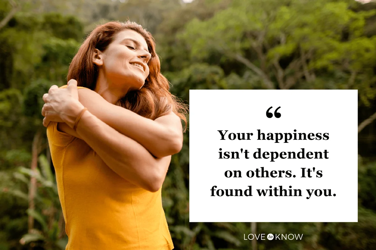 Smiling woman giving herself a hug outside in summer