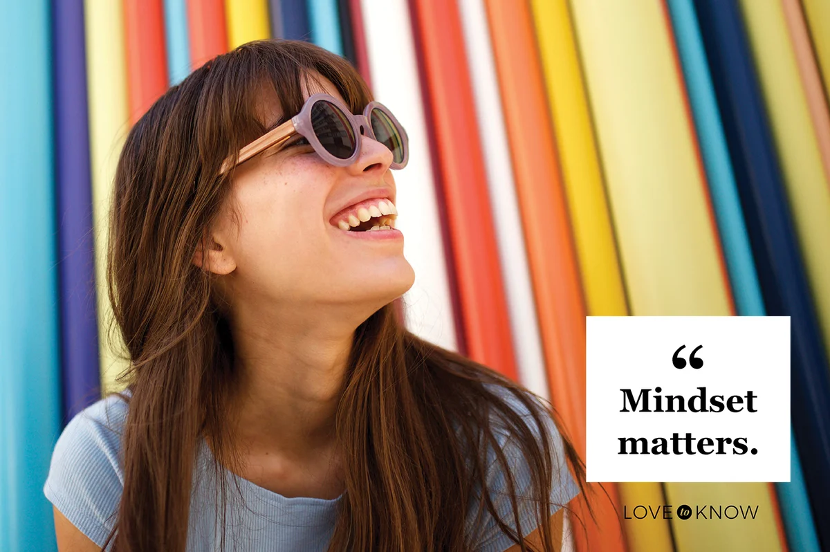 Cheerful young woman laughing with sunglasses against colourful background