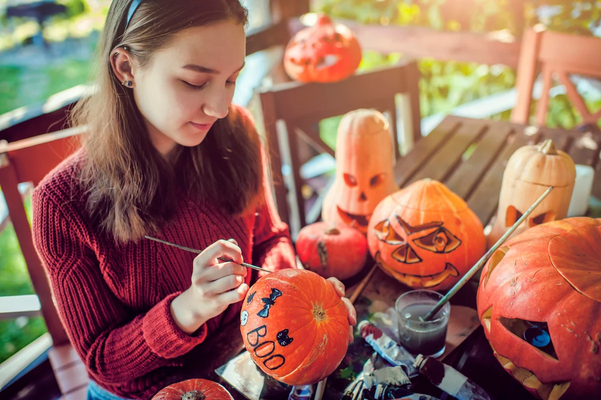 Young girl painting on pumpkin in Halloween