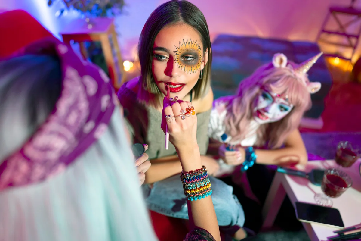 Girls preparing for Halloween party, doing make-up at party