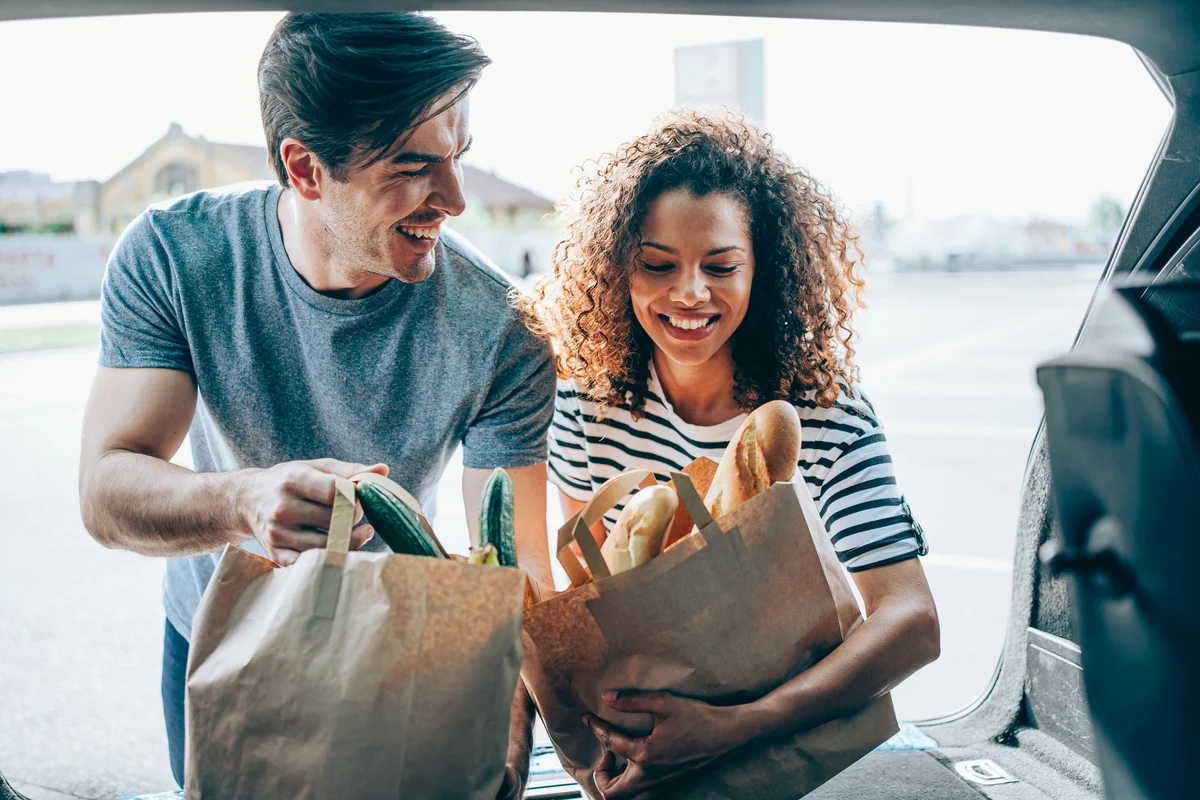 Man and woman packing groceries in car trunk