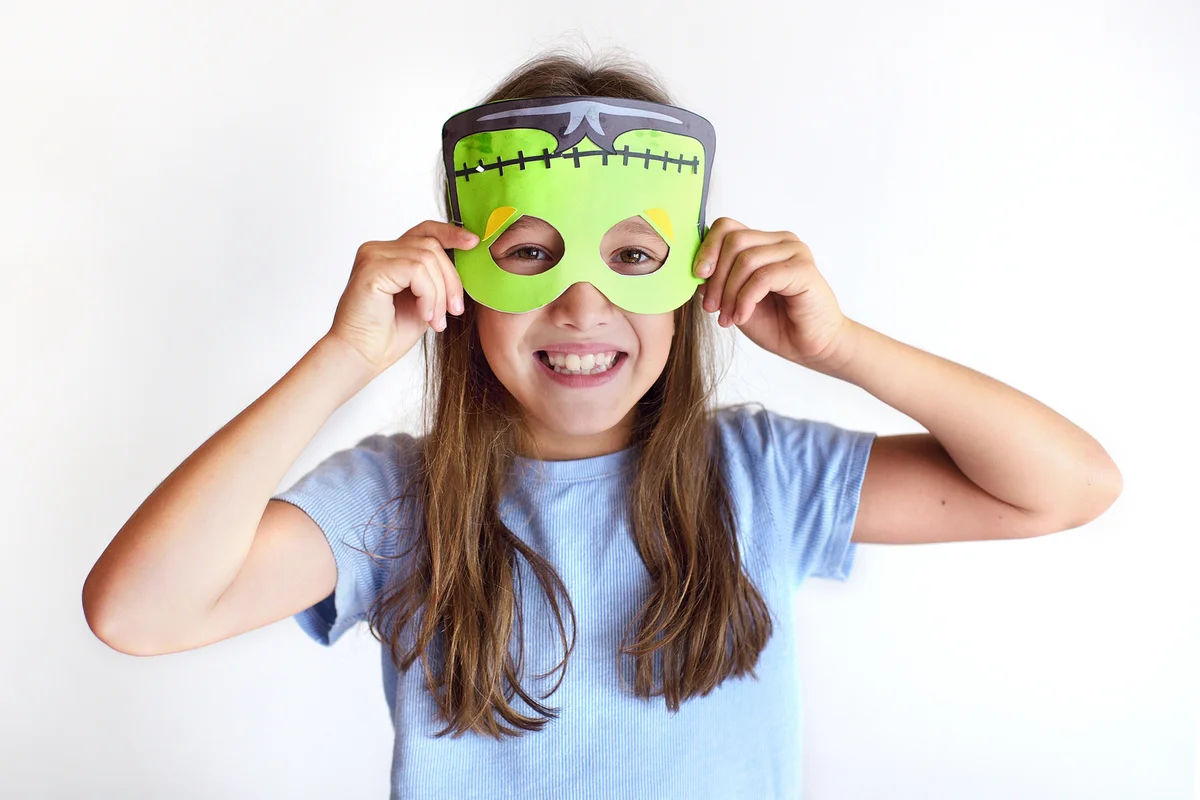 The girl plays the fool in a mask of the monster for Halloween