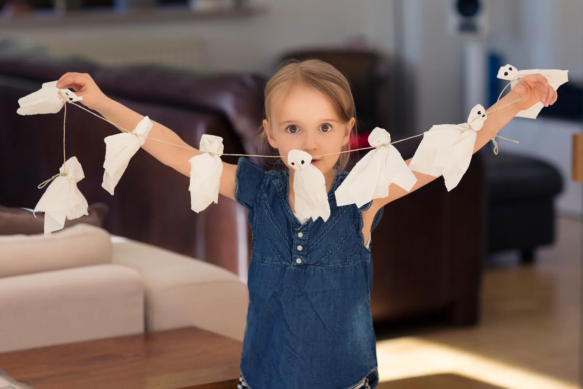 Girl holding up a string of paper halloween ghosts