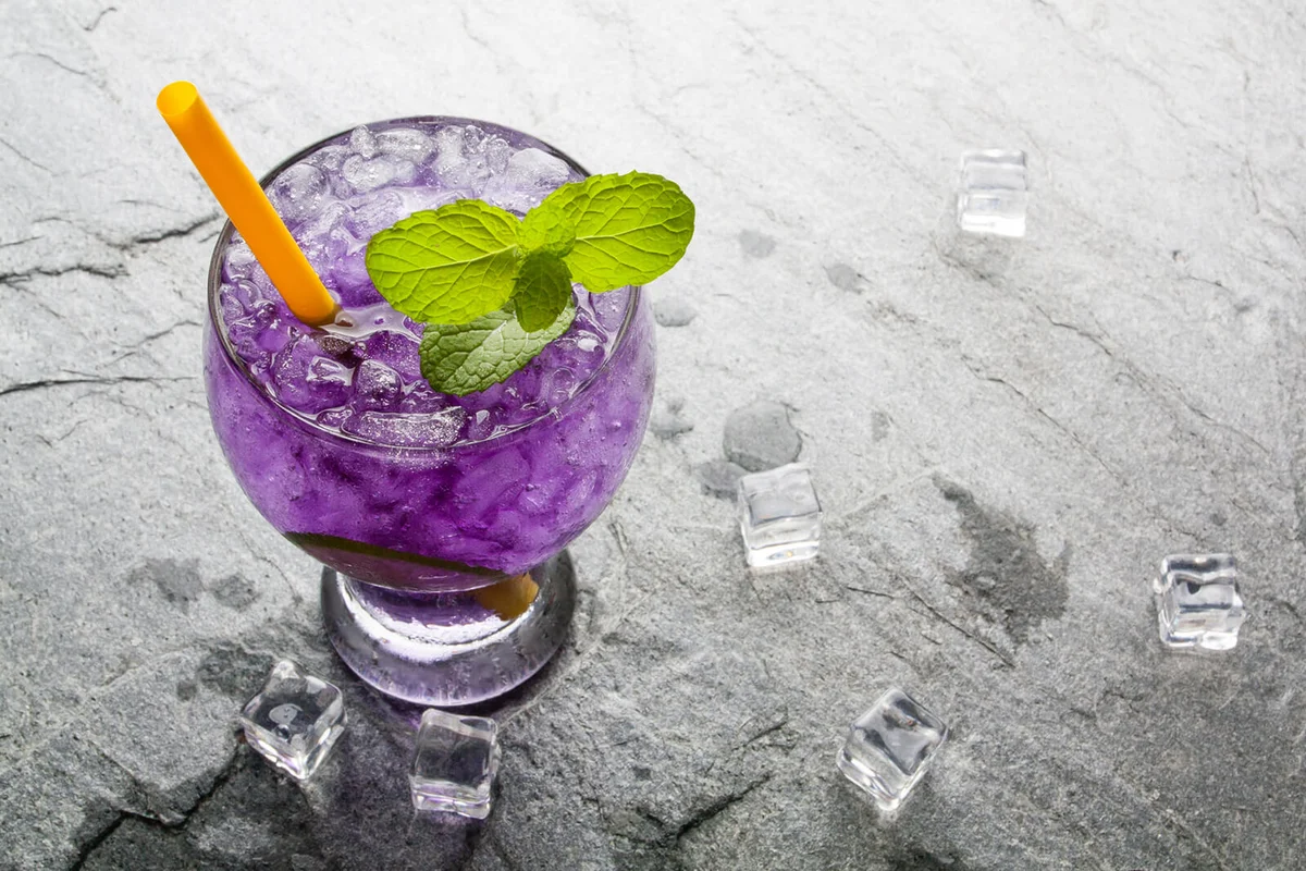 Purple soda lime drink with lime on stone