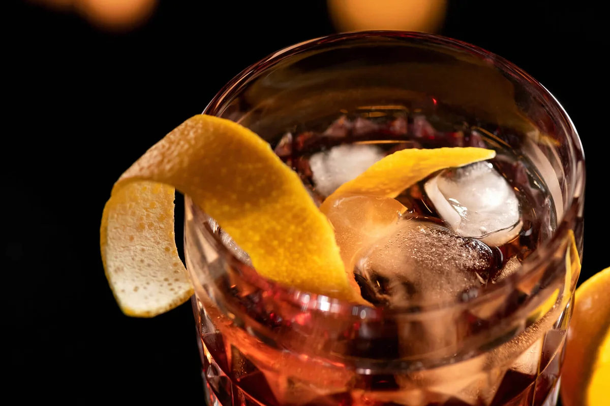 Whiskey with orange zest and ice cubes in glass