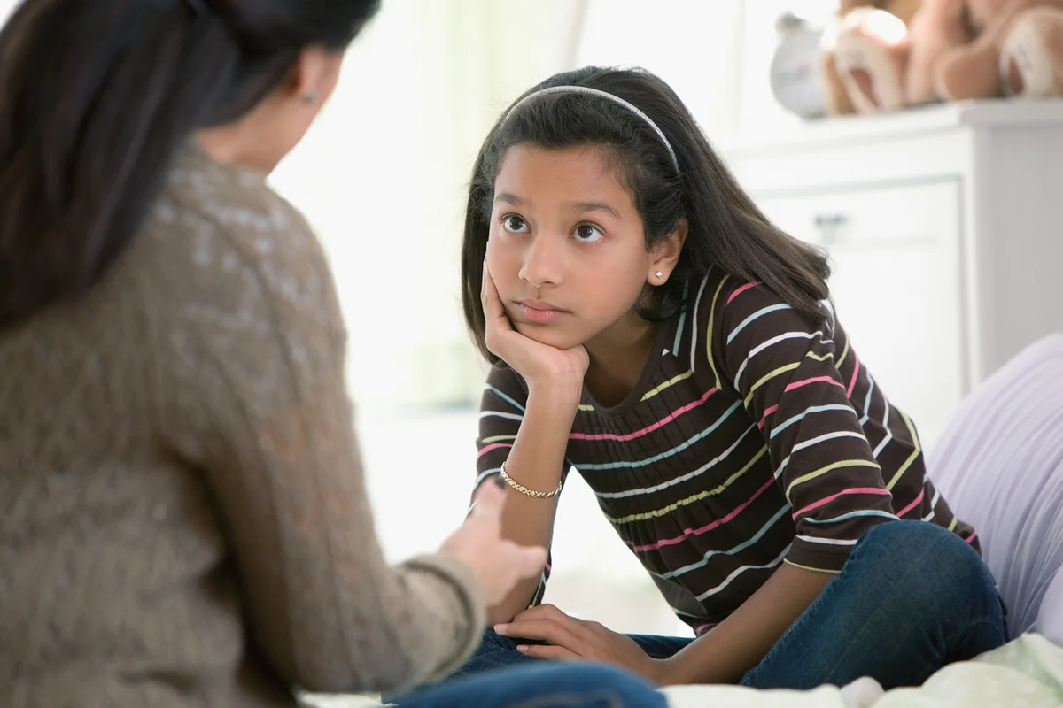 Mother talking to daughter in bedroom