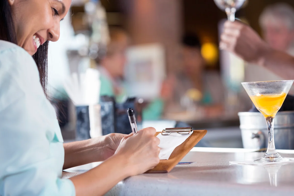 Woman signing receipt after paying bar tab